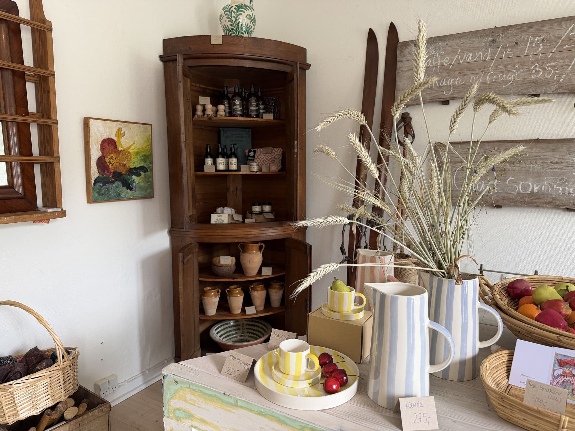 An antique corner cabinet with soap, ceramics and old jugs