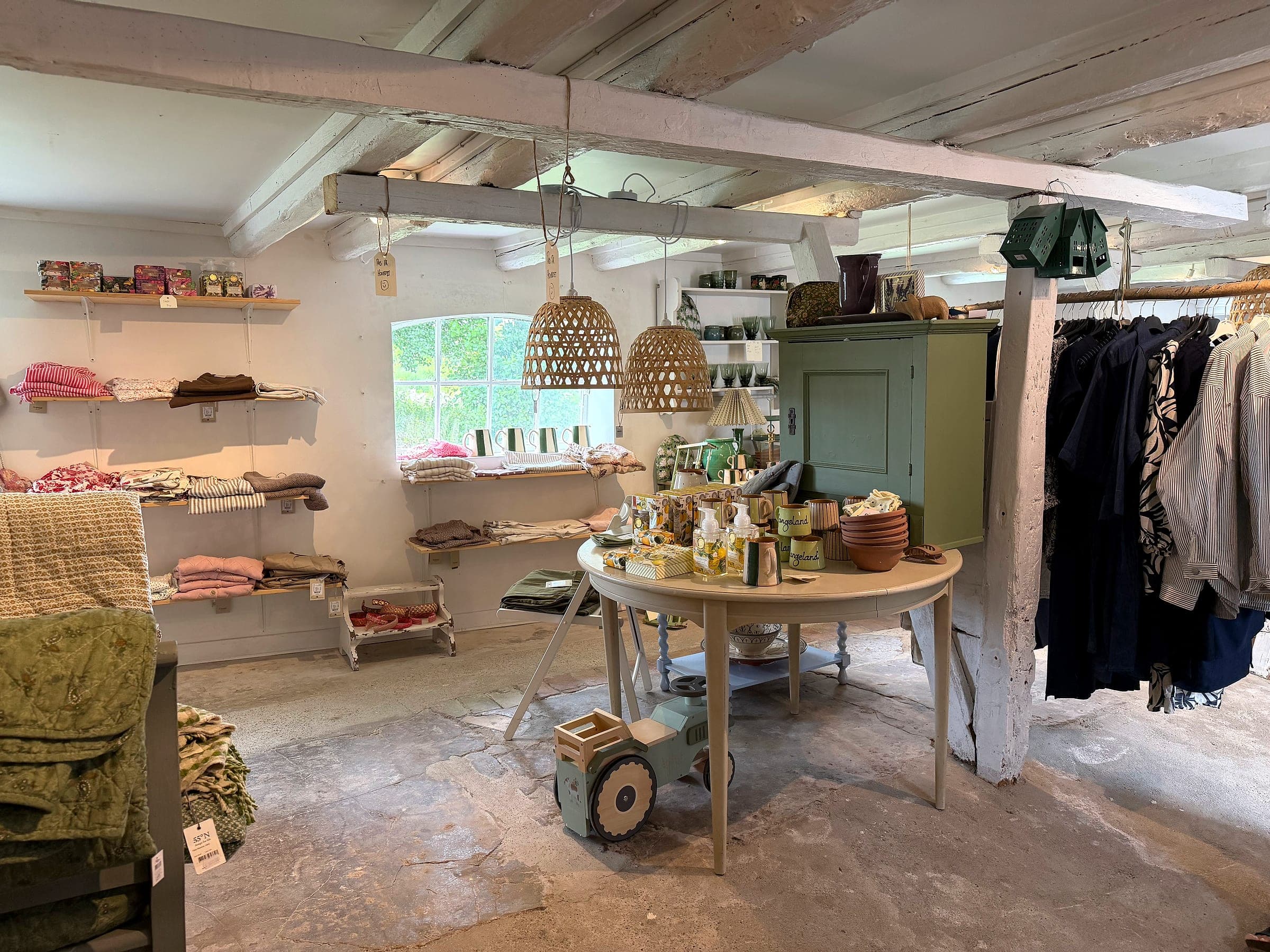 Runder Tisch mit Geschenkartikeln, mit Kleidung und einem grünen Schrank im Hintergrund