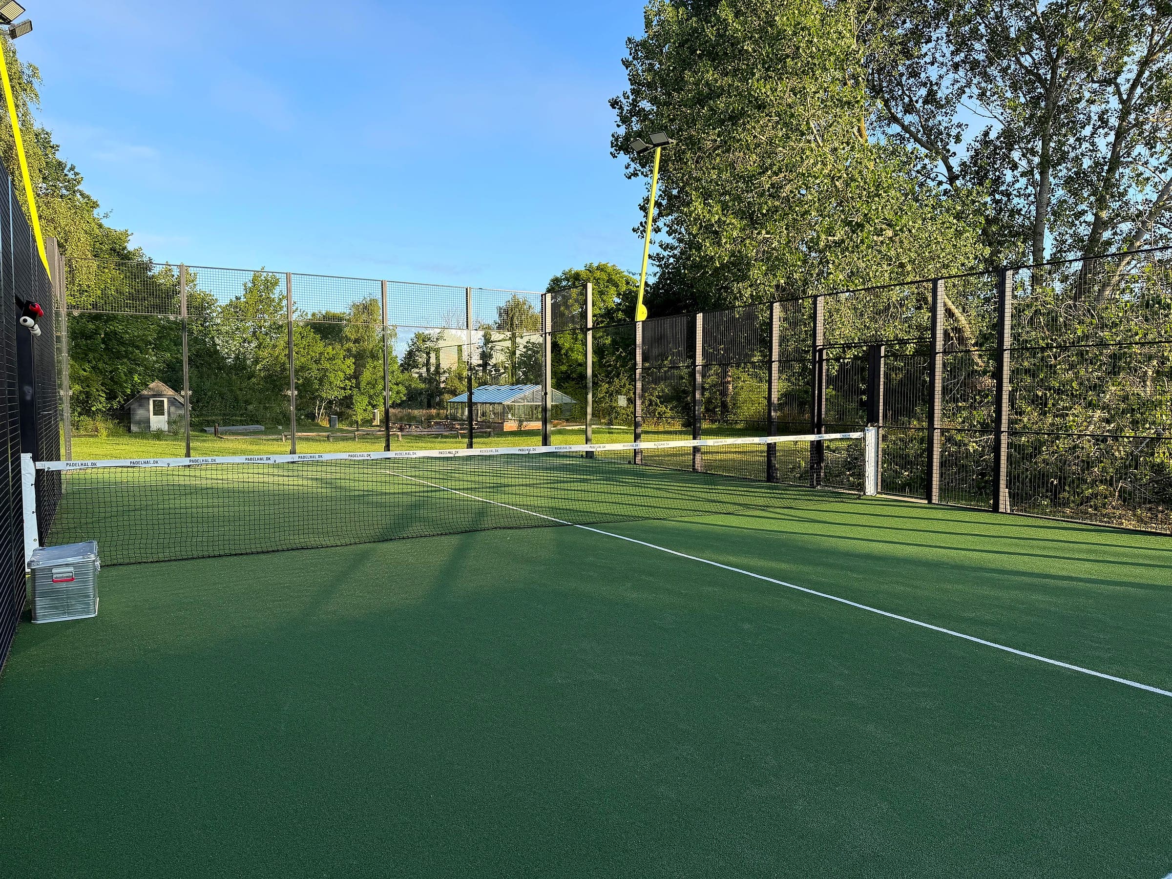 Blick über den Padelplatz mit Kunstrasen und Zaun ringsum