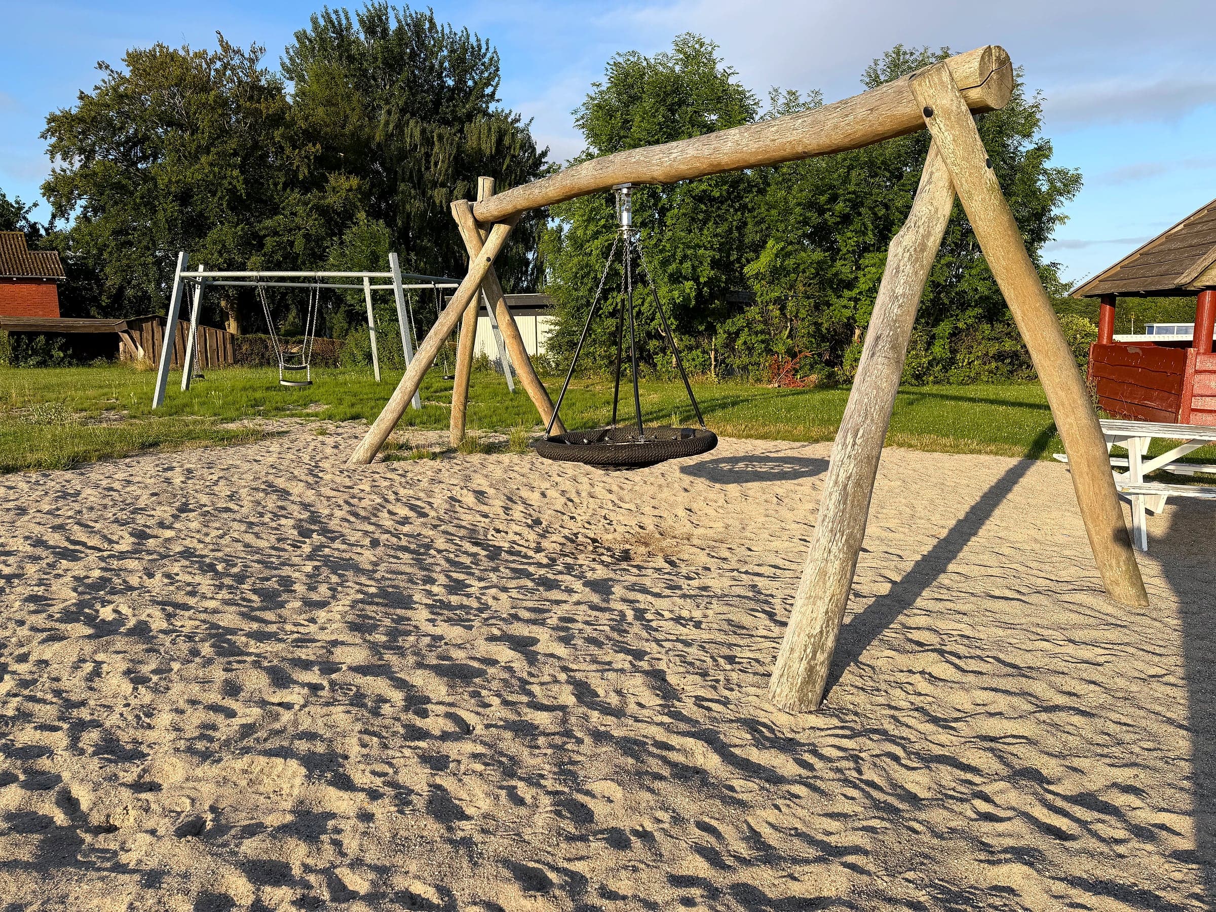 Nestschaukel im Sand mit dem gewöhnlichen Schaukelgestell im Hintergrund