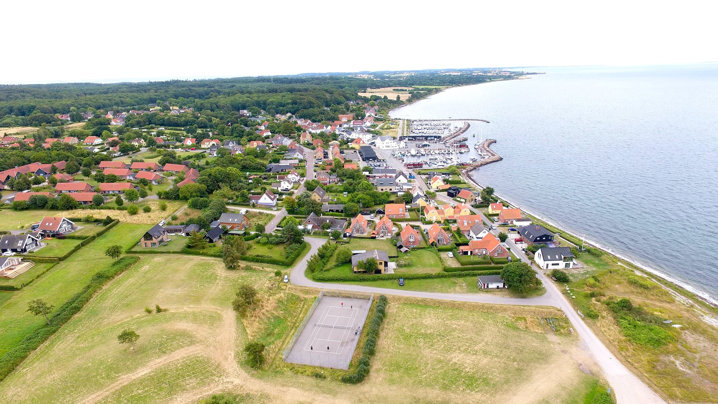 Aerial photo of Lohals with the harbour, the town and the tennis court in the foreground