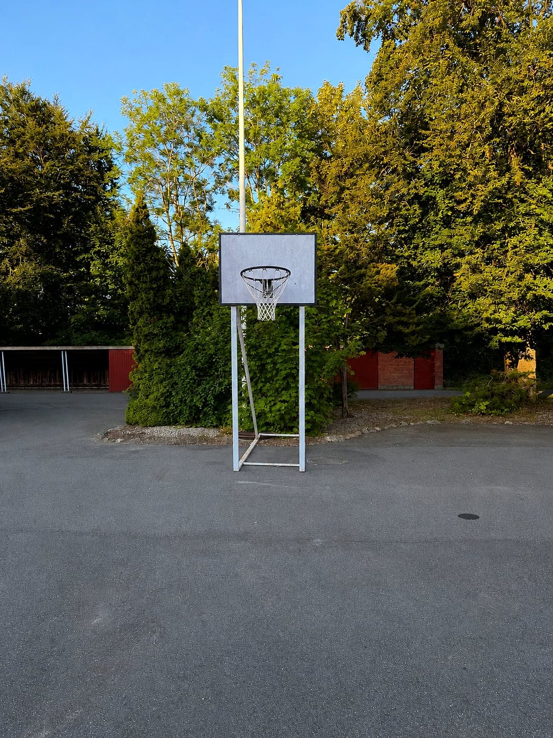 Basketballkorb auf offener Asphaltfläche neben dem Spielplatz Hou