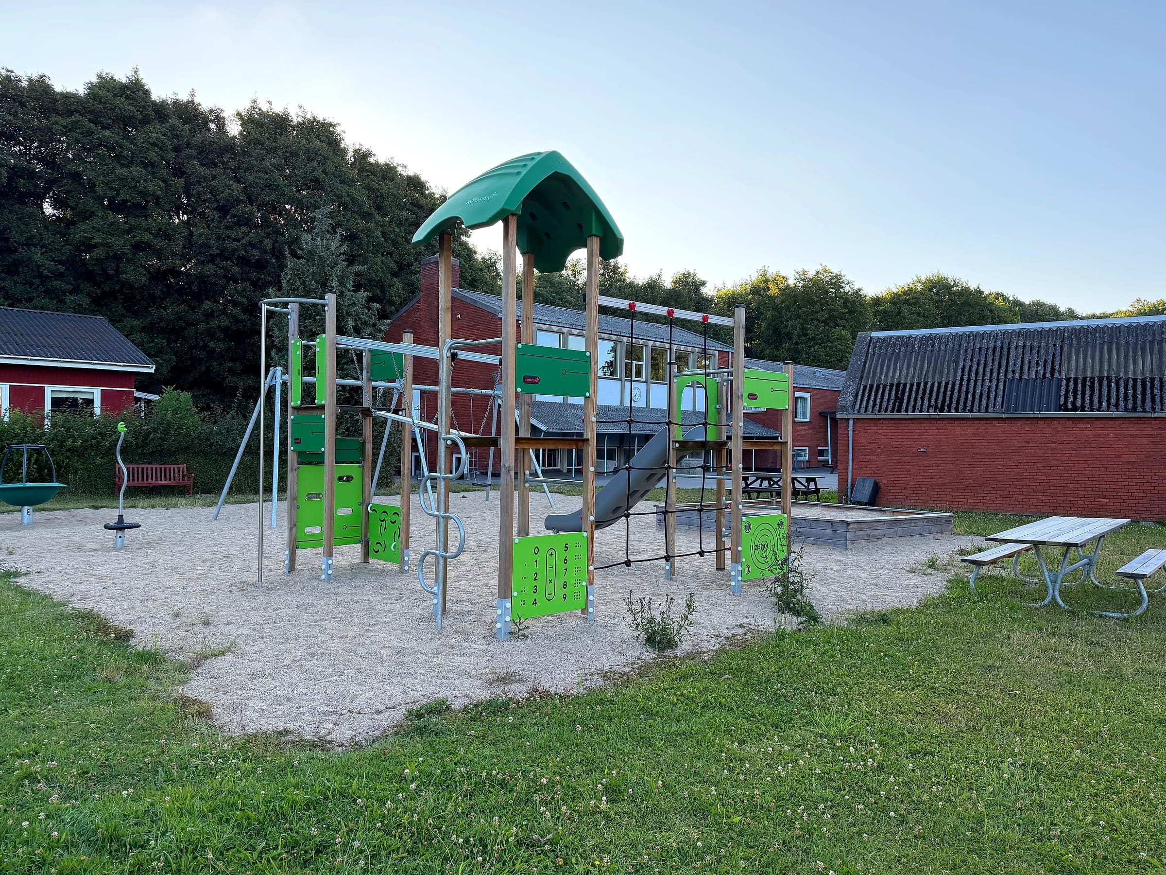 Spielturm mit Rutsche, Kletternetz und Schaukeln auf dem Spielplatz Hou