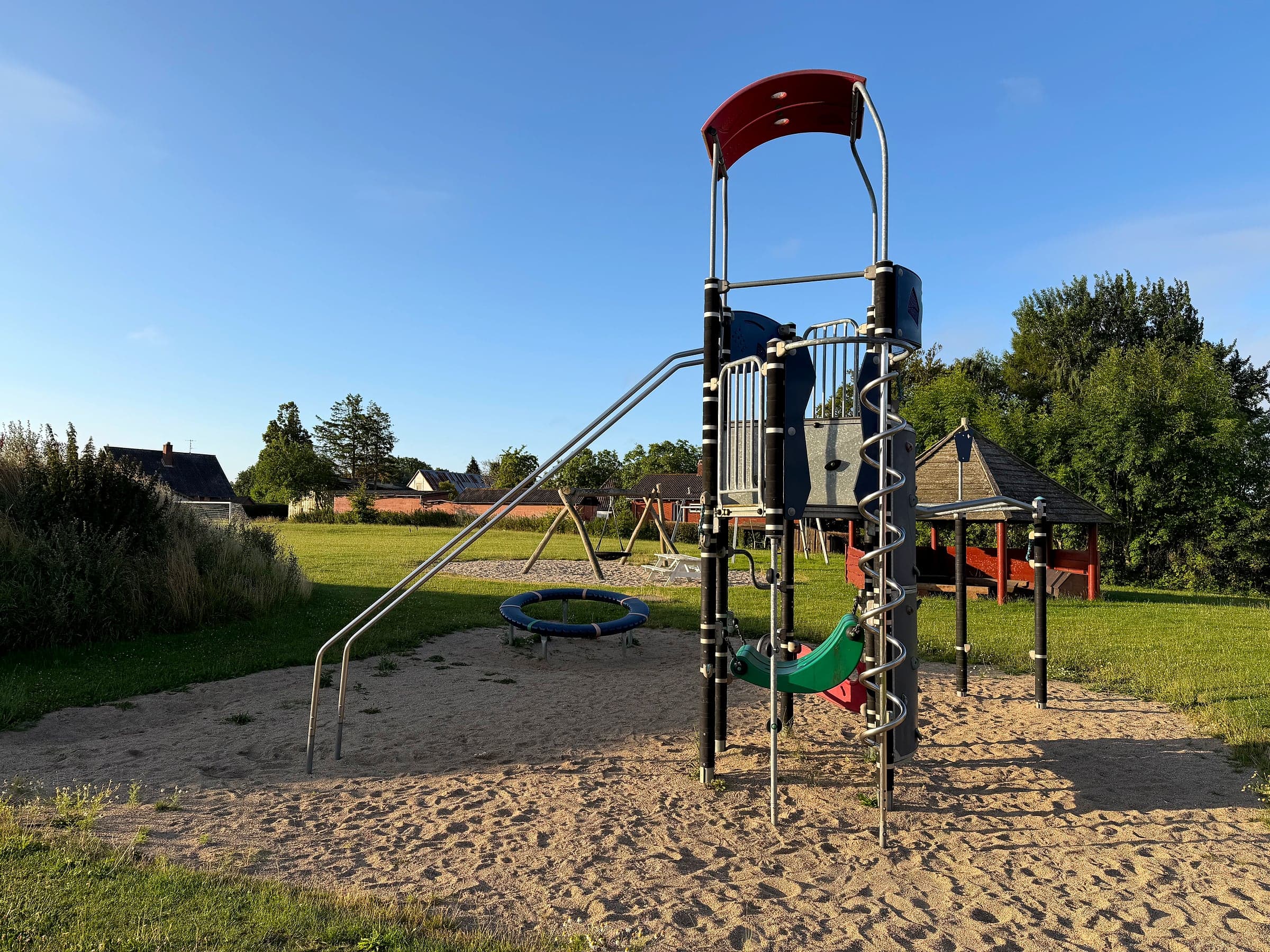 Kletterturm mit Rutsche, Spinnennetz und Trampolin auf dem Spielplatz Snøde