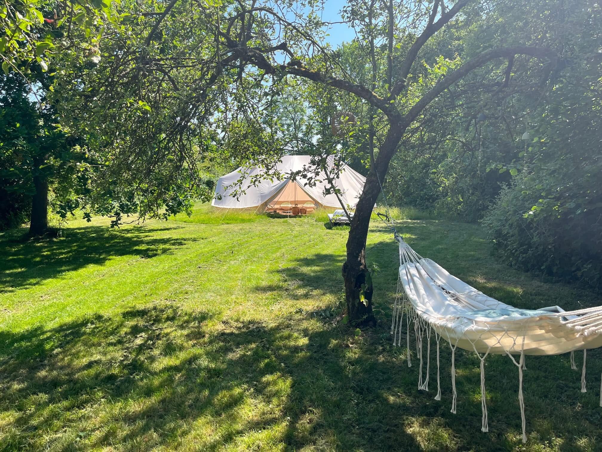 Das Yogazelt von außen im grünen Garten mit einer Hängematte im Vordergrund